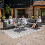 Grey outdoor corner sofa set with black metal frame and coffee table on patio tiles