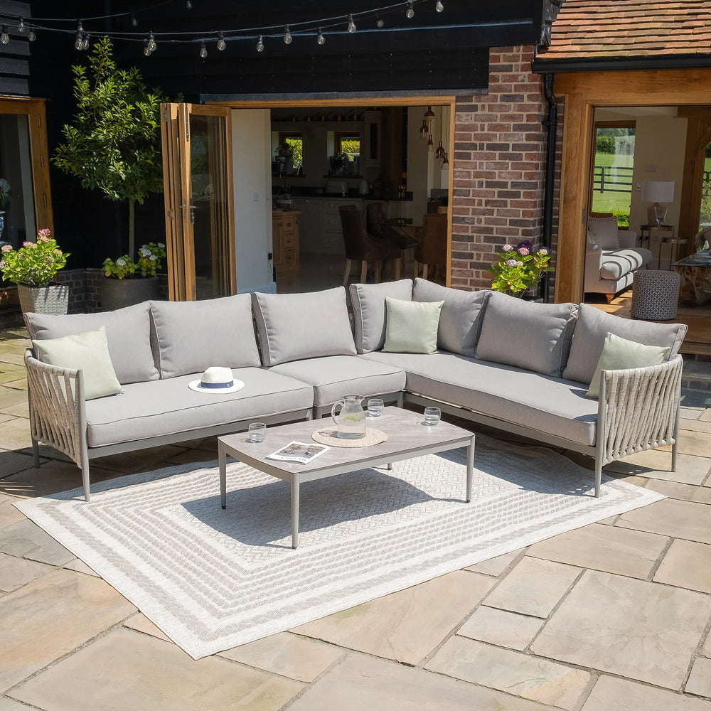 Grey outdoor corner sofa set with cushions and coffee table on patio rug