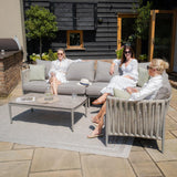 Grey outdoor sofa set with rope detailing and coffee table on patio, three women seated