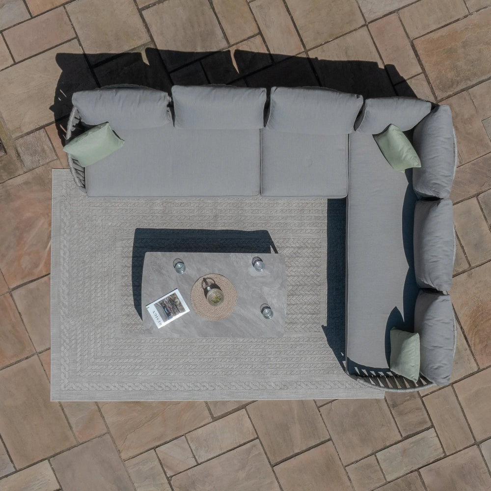 Grey outdoor corner sofa with cushions and coffee table on patio tiles