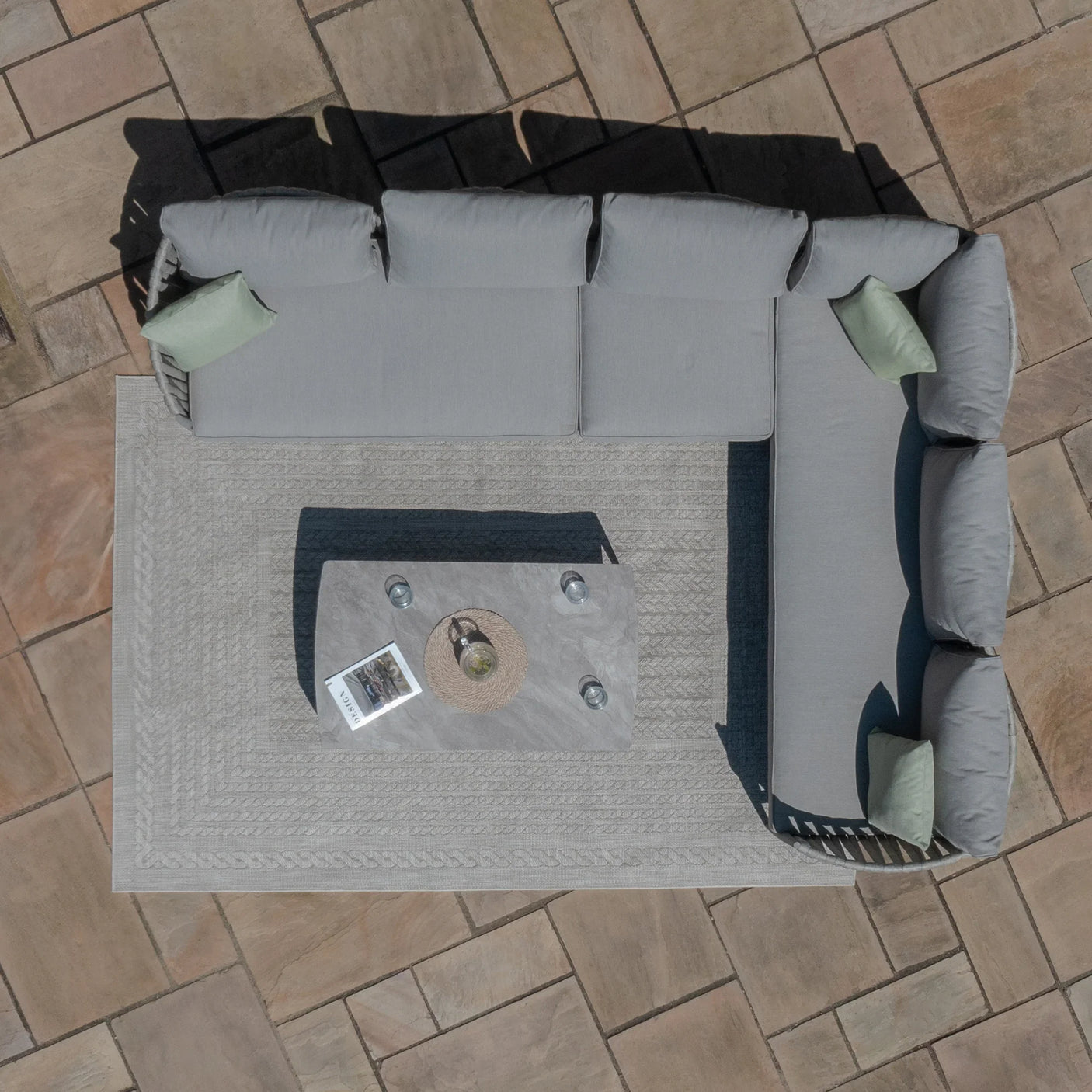 Grey outdoor corner sofa with cushions and coffee table on patio tiles