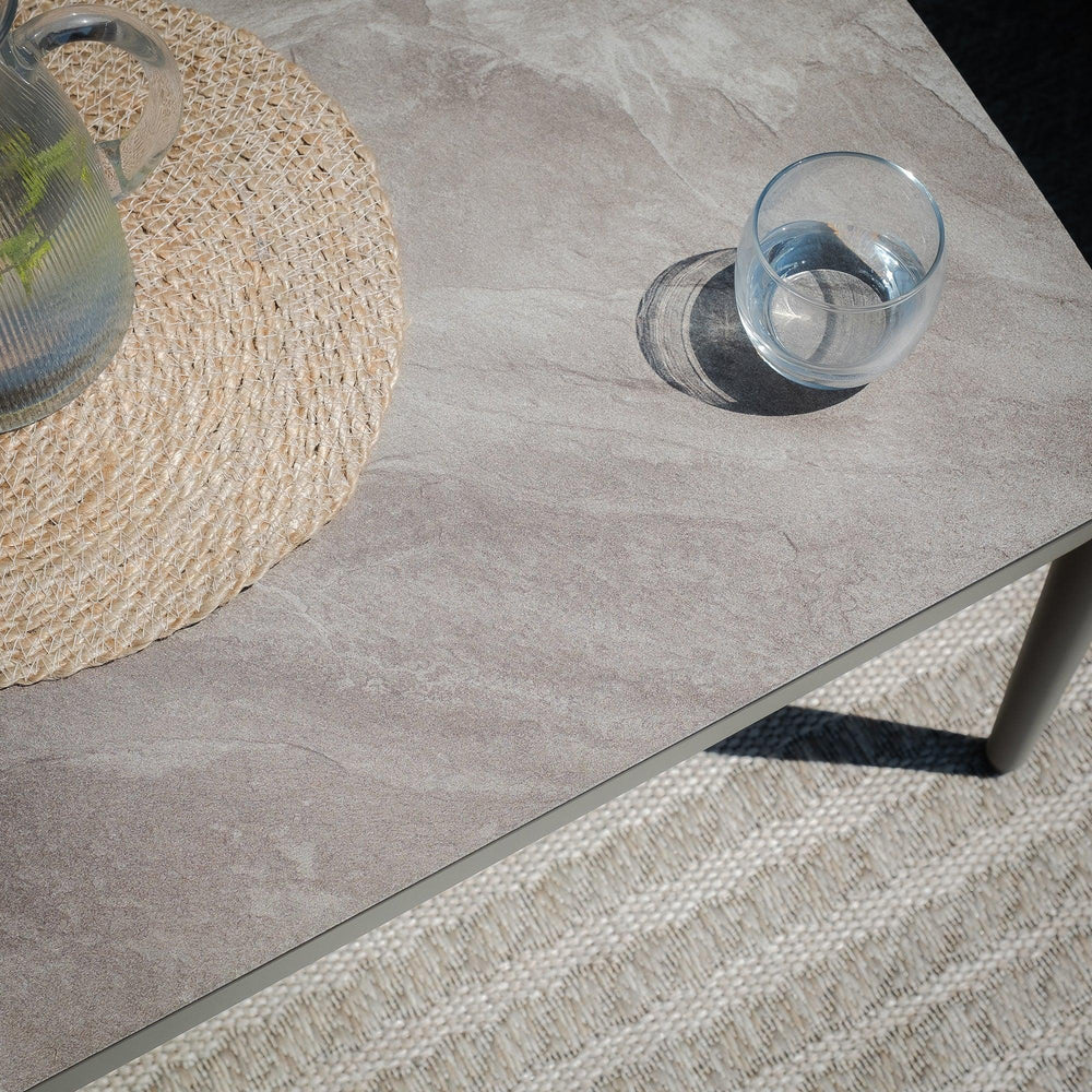 Grey stone-effect dining table top with glass tumbler and woven placemat