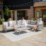 Grey outdoor corner sofa set with cushions and coffee table on a stone patio