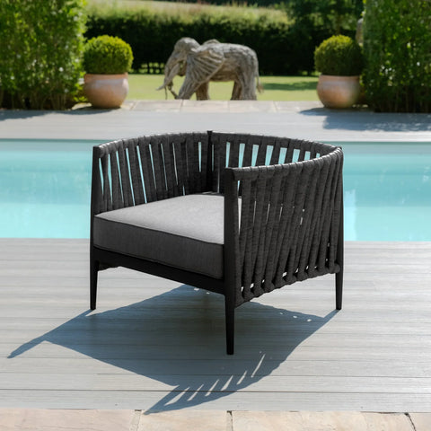 Outdoor lounge chair with dark woven rope frame and grey cushion by a pool on decking