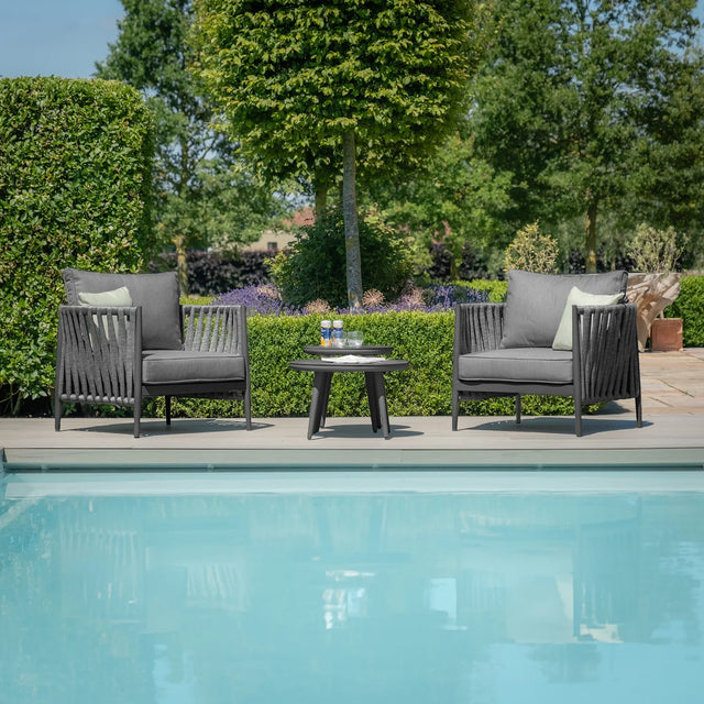 Outdoor rope armchairs and round table set beside pool on garden patio