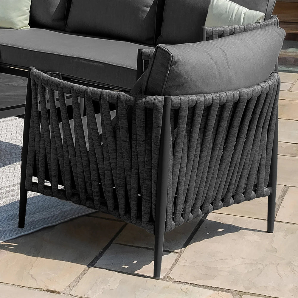 Dark grey outdoor lounge chair with woven rope back and seat cushions on patio tiles