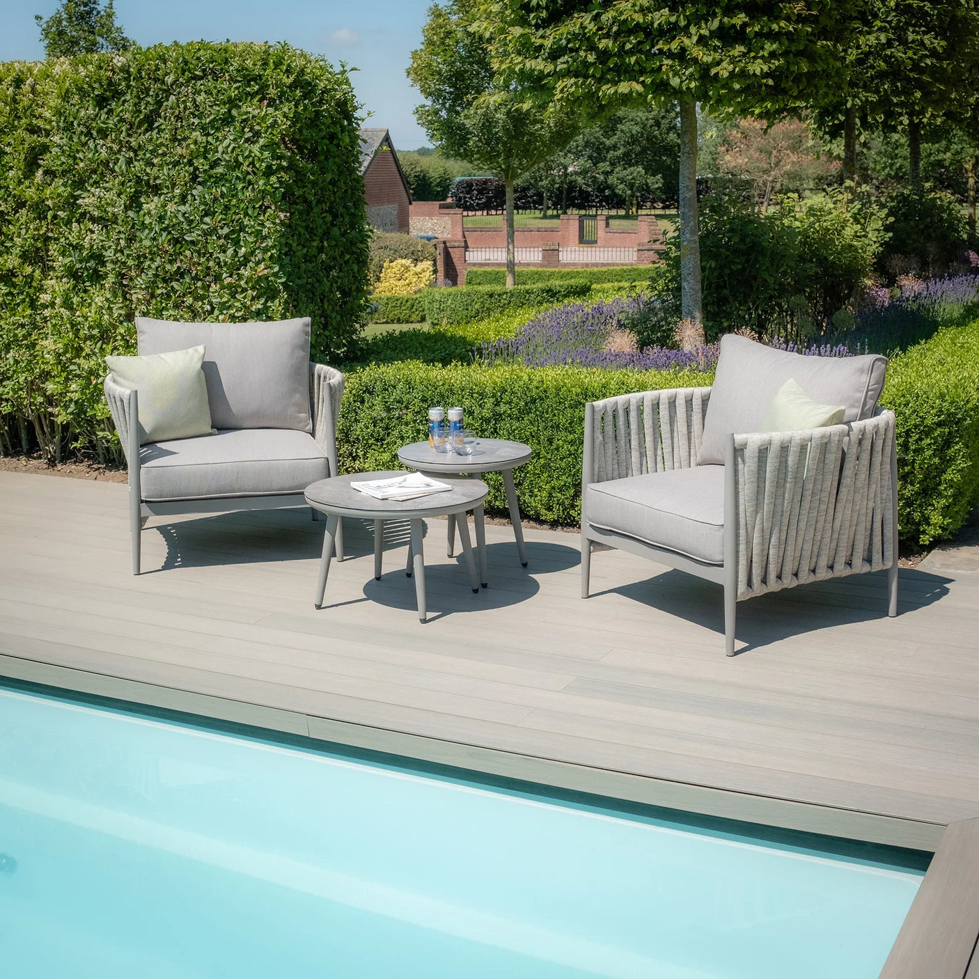 Outdoor garden furniture set with two grey lounge chairs and tables by poolside