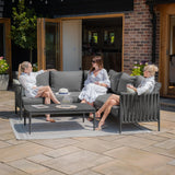 Grey outdoor corner sofa set with coffee table and three women relaxing on patio