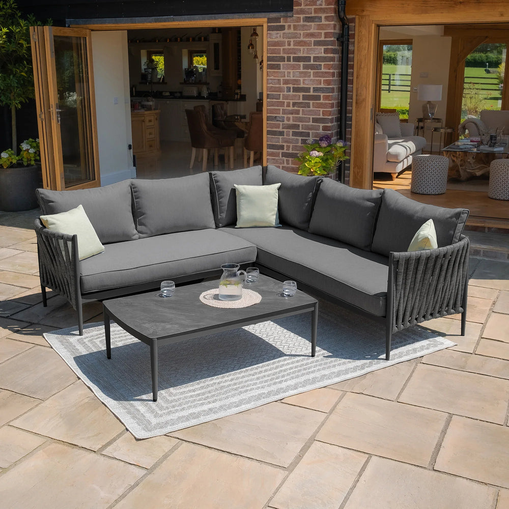 Grey outdoor corner sofa set with cushions and coffee table on patio