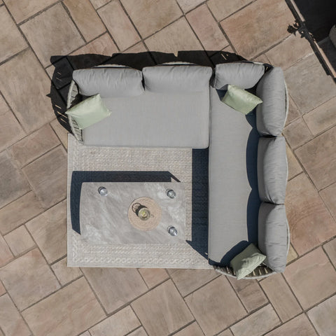 Grey outdoor corner sofa set with cushions and coffee table on patio tiles