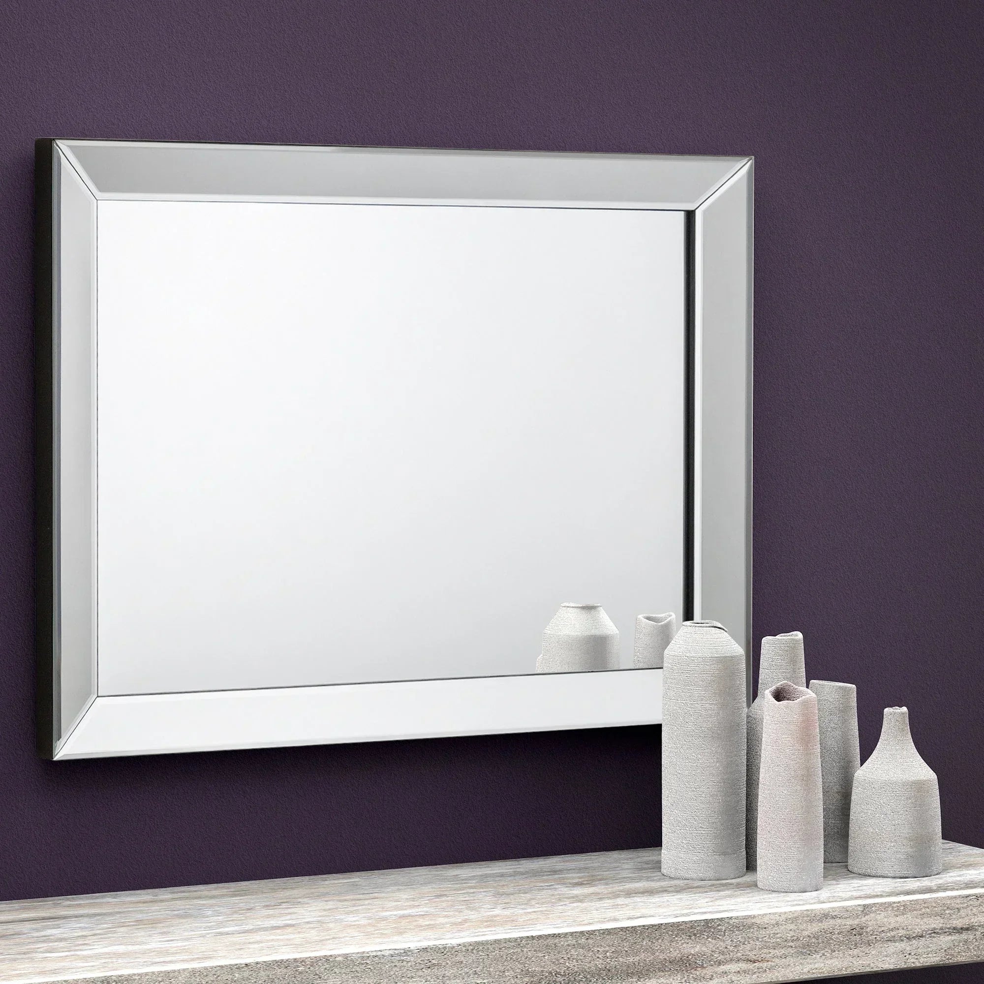 Soprano wall mirror with beveled edge above console table and ceramic vases on purple wall