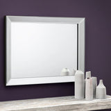 Soprano wall mirror with beveled edge above console table and ceramic vases on purple wall
