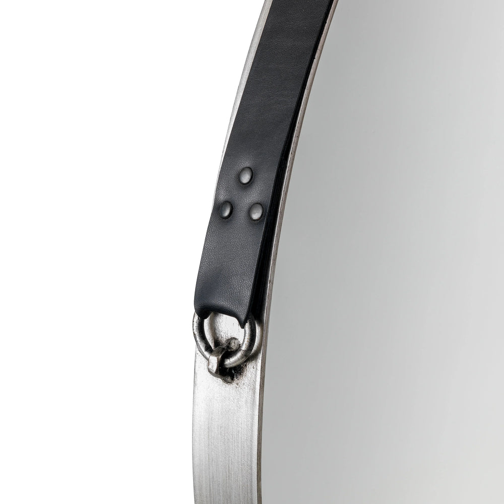 Round wall mirror with metal frame and black leather hanging strap detail close-up