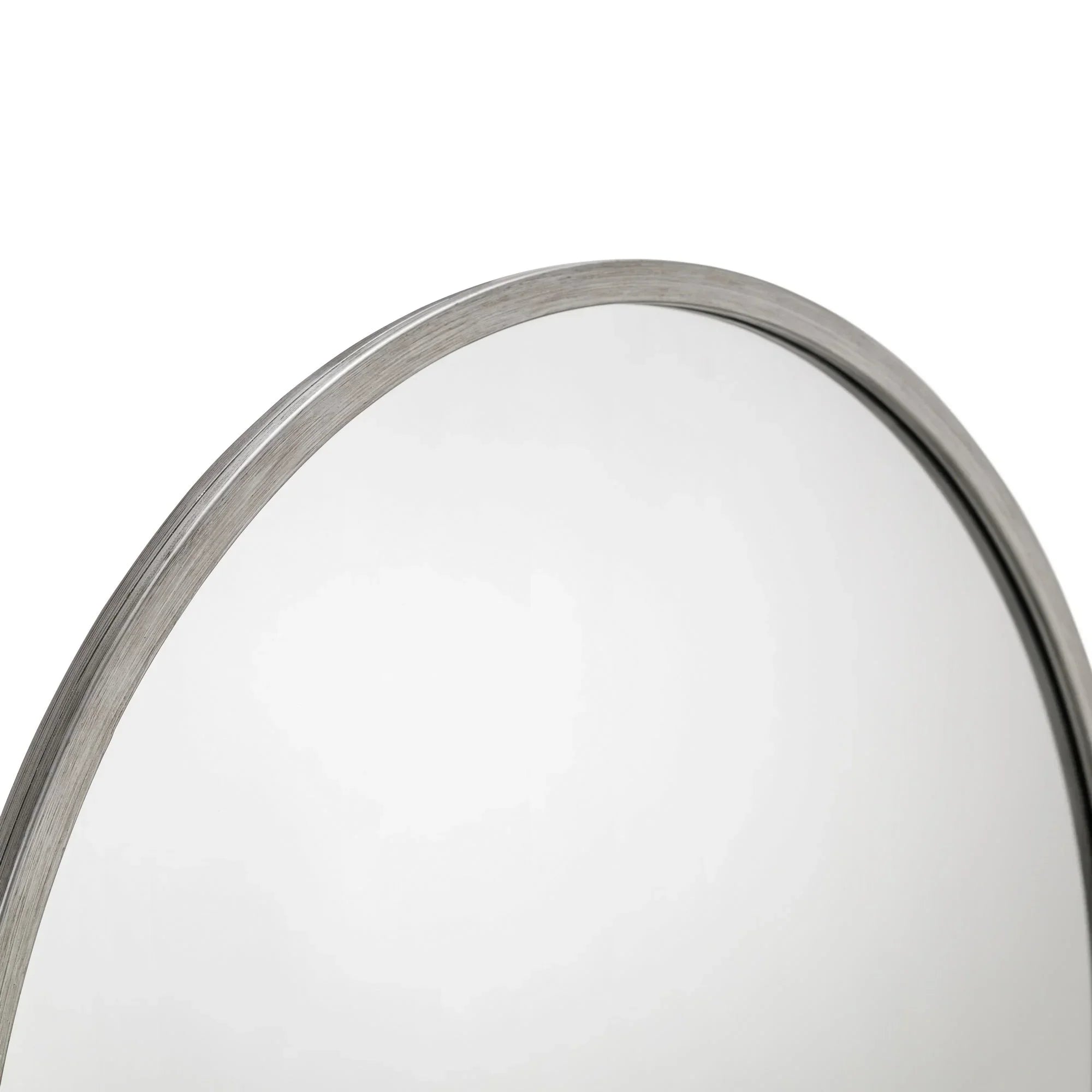 Close-up of round pewter mirror frame with brushed metallic finish