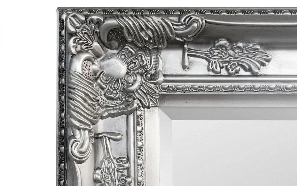 Close-up of ornate silver mirror frame corner with floral and scroll detail