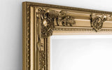Close up of ornate gold wall mirror frame with floral decorative detailing