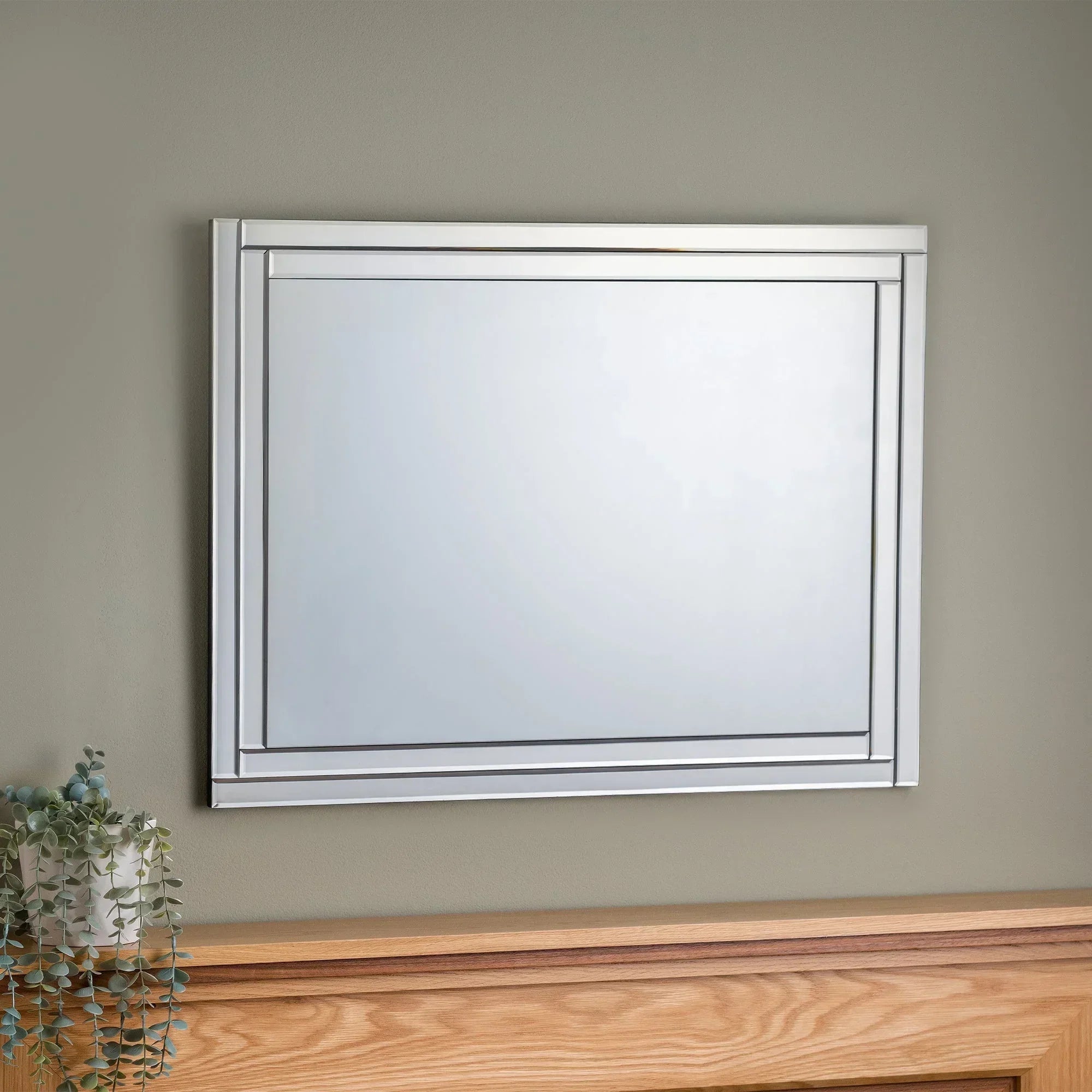Deco frameless wall mirror with metallic edge above wooden headboard, modern interior
