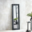 Black ornate full length mirror leaning against textured wall in modern living room