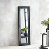 Black ornate full length mirror leaning against textured wall in modern living room