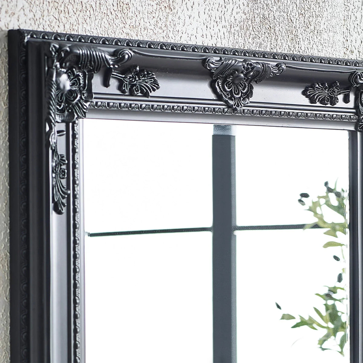 Black ornate mirror frame with decorative floral detailing against textured wall