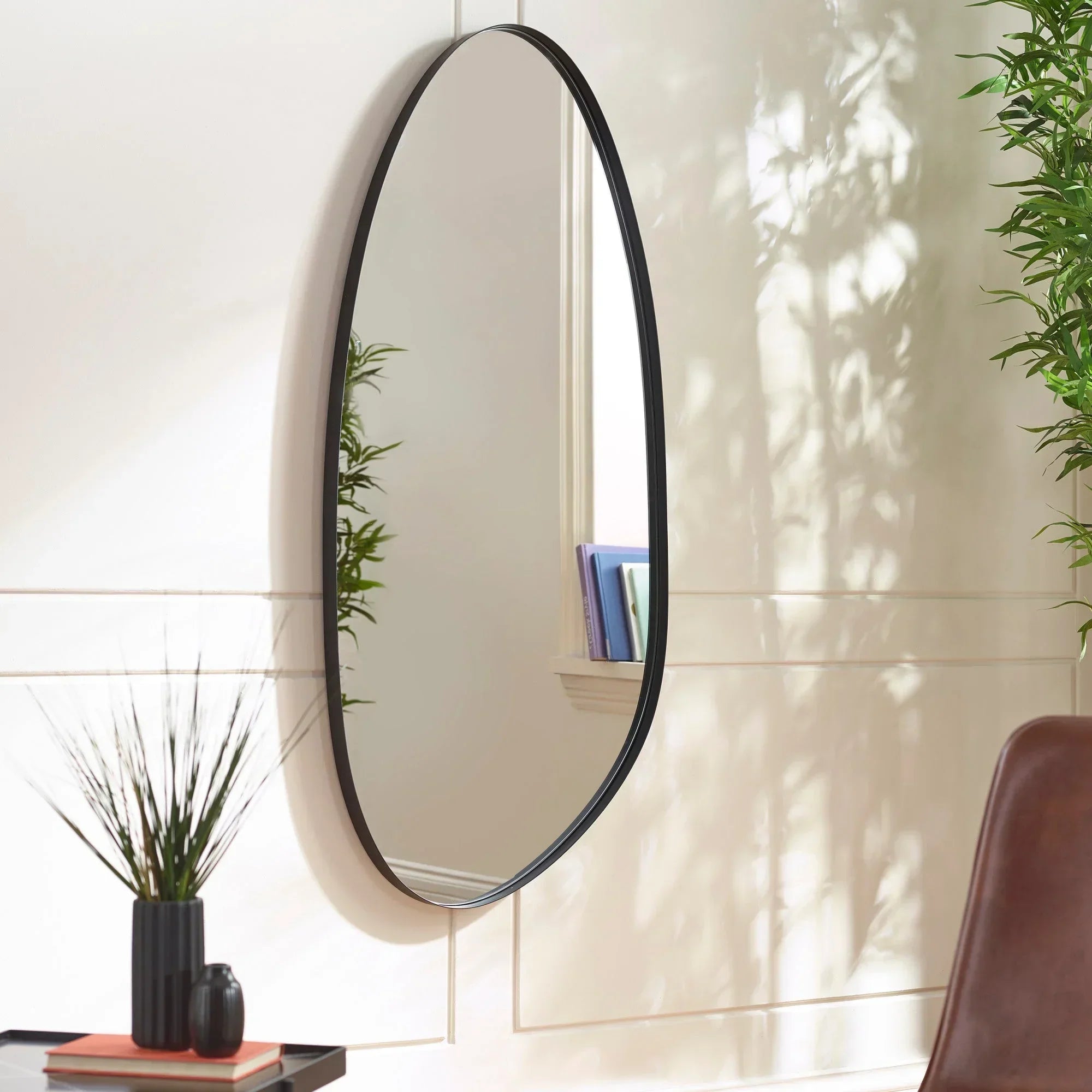 Oval wall mirror with slim black frame in modern living room setting