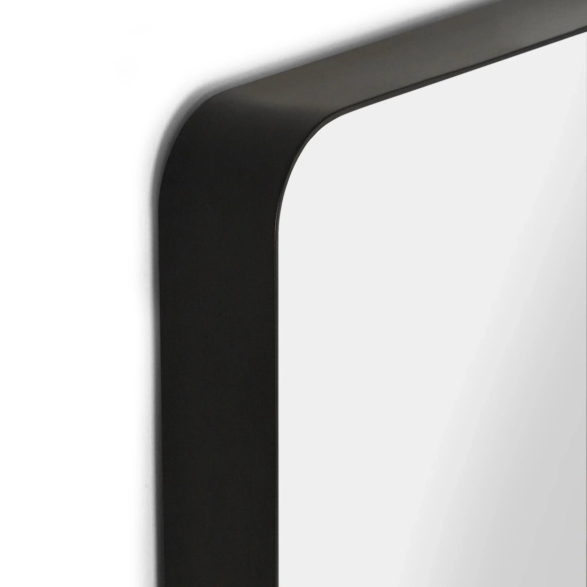 Closeup of black metal frame mirror with rounded corner on white wall