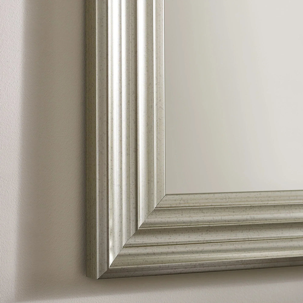 Silver wall mirror with grooved rectangular frame on beige wall