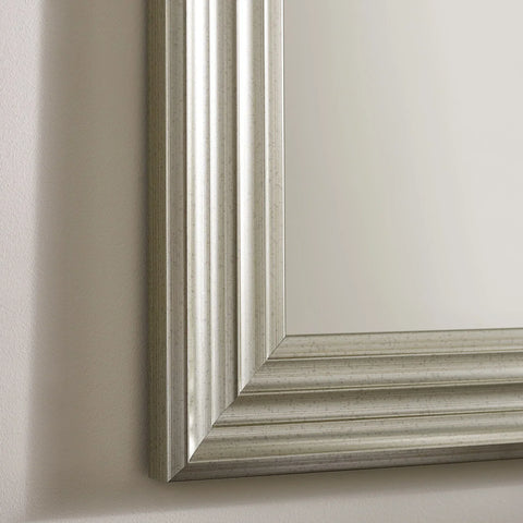 Silver wall mirror with grooved rectangular frame on beige wall