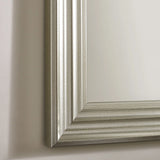 Silver wall mirror with grooved rectangular frame on beige wall