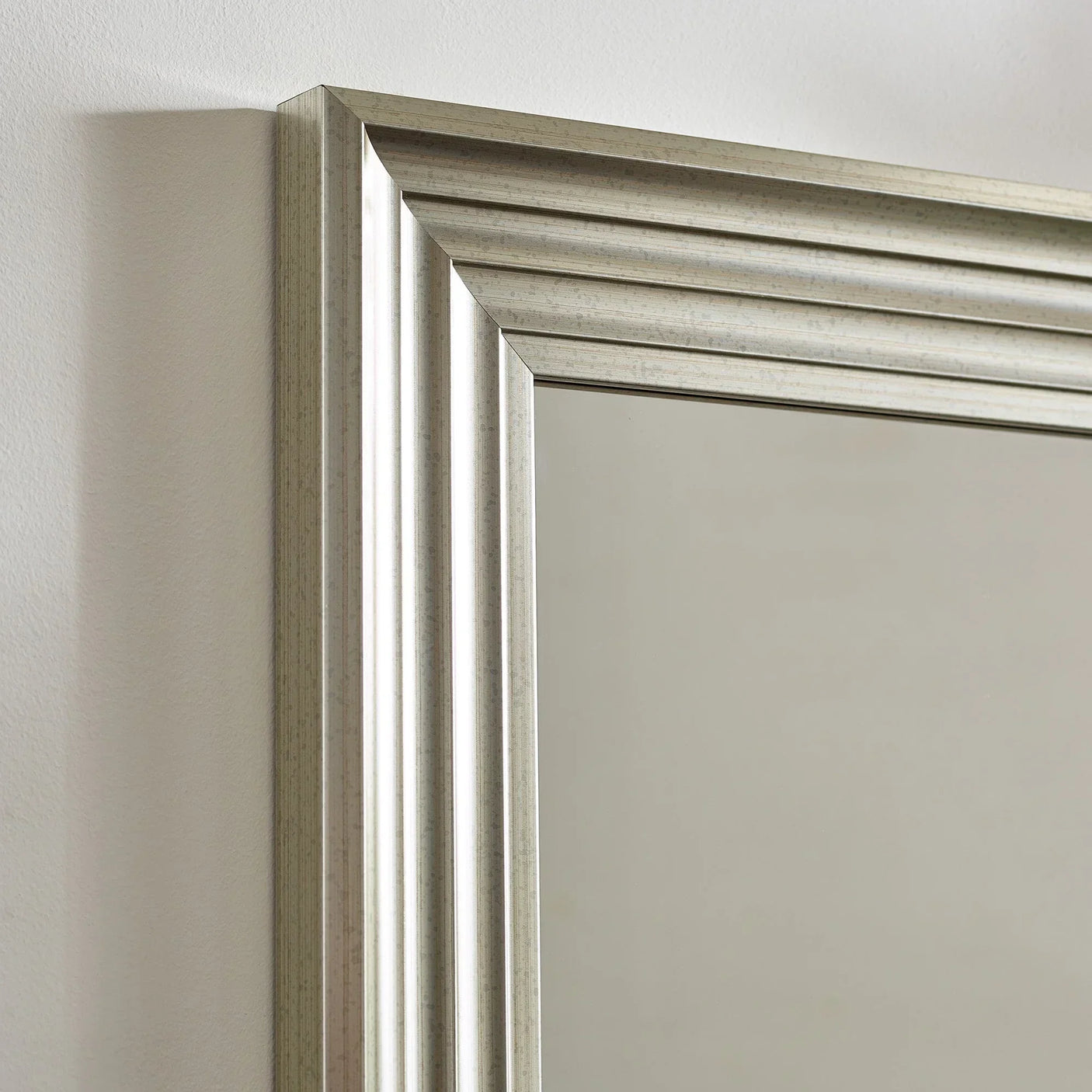 Silver wall mirror with bevelled edge frame against white background