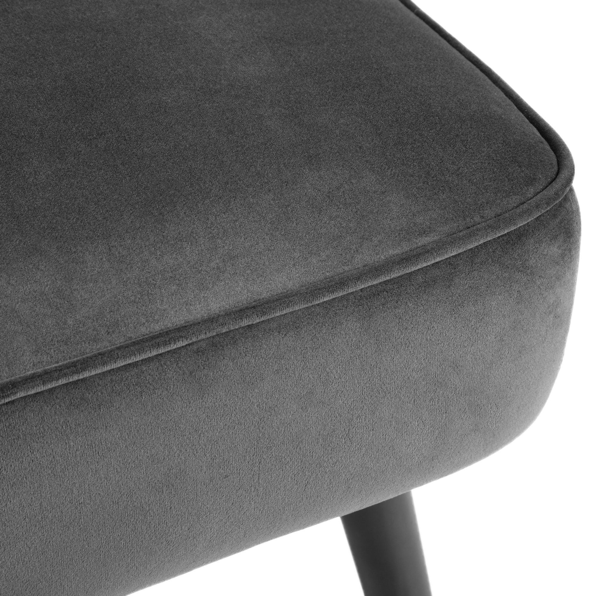 Closeup of dark grey velvet dining chair seat with black tapered leg