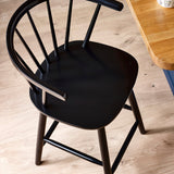 Close-up of black wooden bar stool curved spindle backrest and smooth seat surface in kitchen
