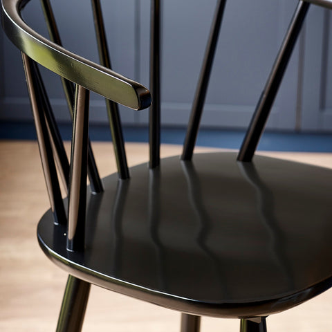 Close-up detail of black wooden bar stool spindle backrest with shiny finish beside wood countertop