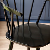 Close-up detail of black wooden bar stool spindle backrest with shiny finish beside wood countertop