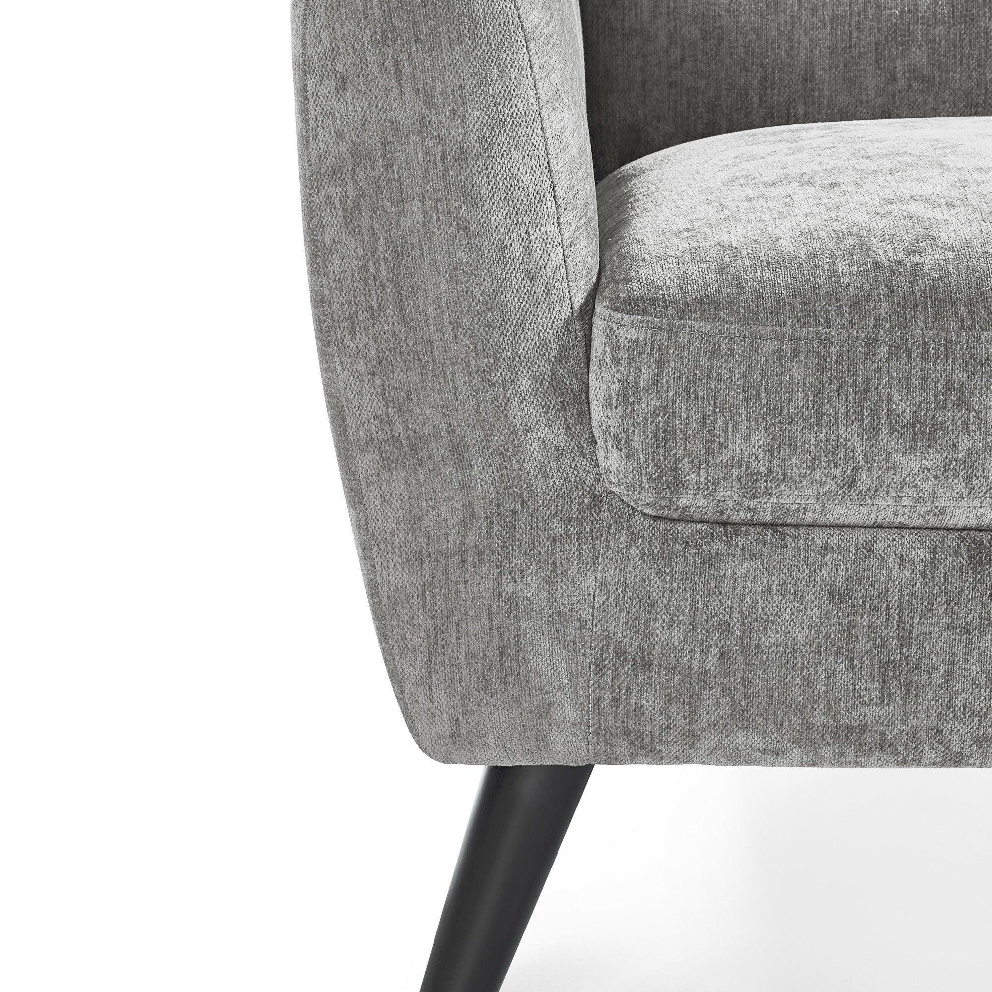 Close view of grey fabric armchair with tapered black leg and curved armrest