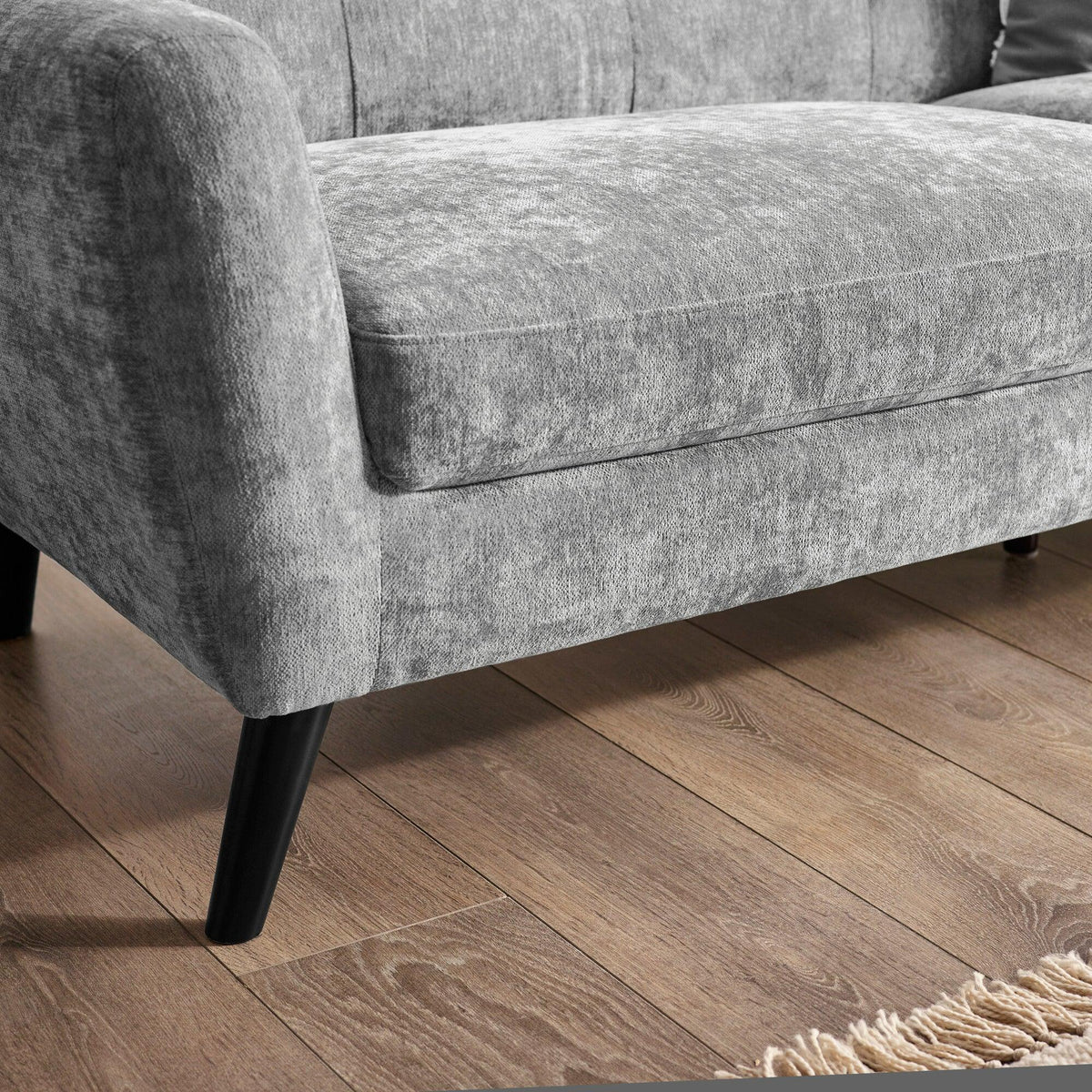 Grey fabric sofa with black tapered legs on wooden floor