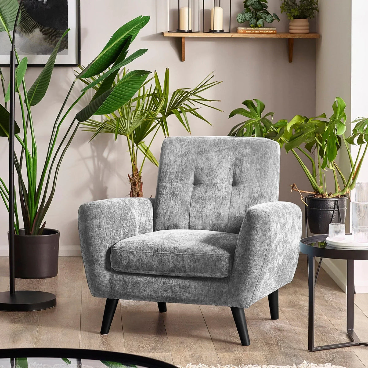 Grey velvet armchair with buttoned backrest in modern living room with potted plants