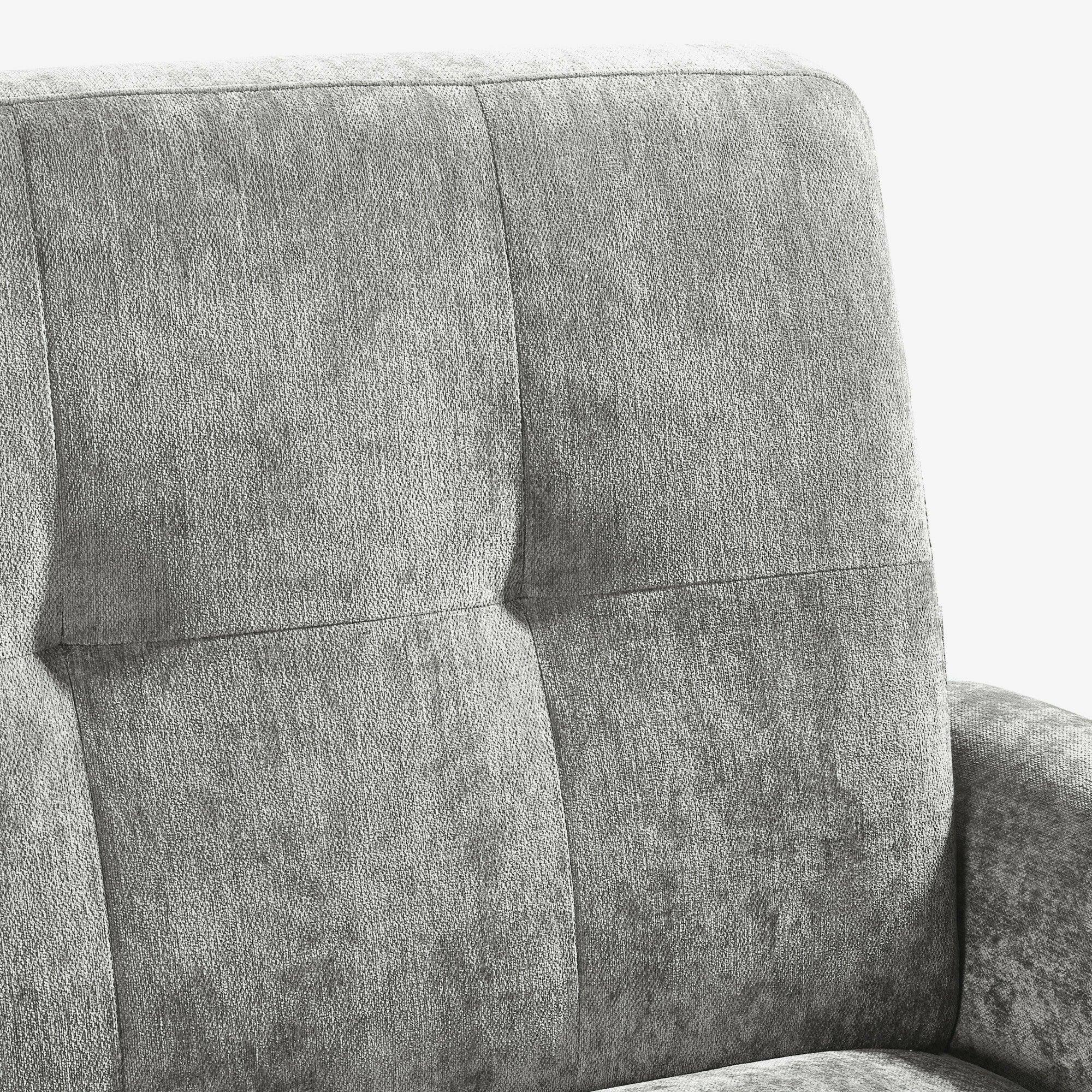 Grey fabric sofa backrest with stitched square pattern and padded armrest close-up
