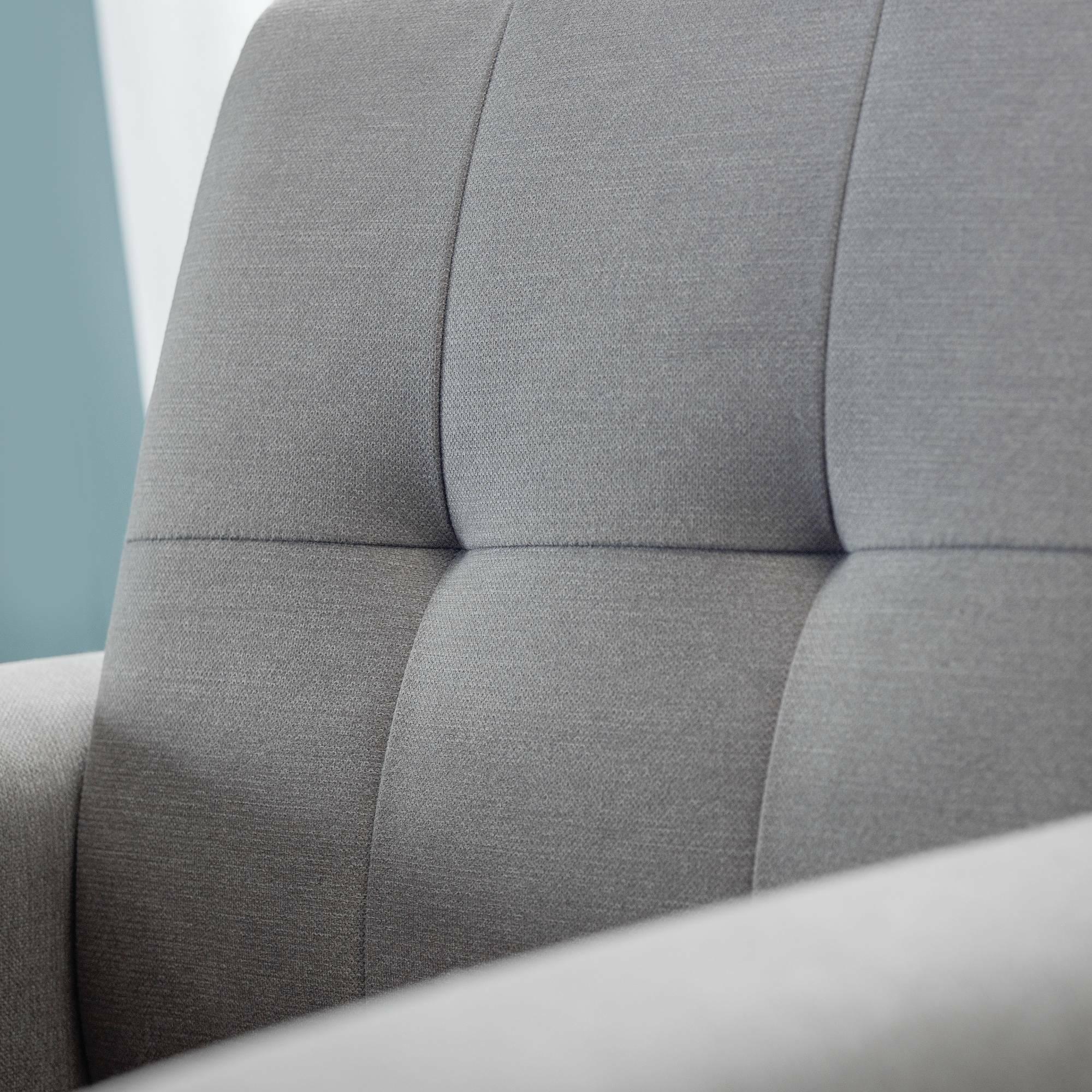Close-up of grey fabric two seater chair with stitched button back detail