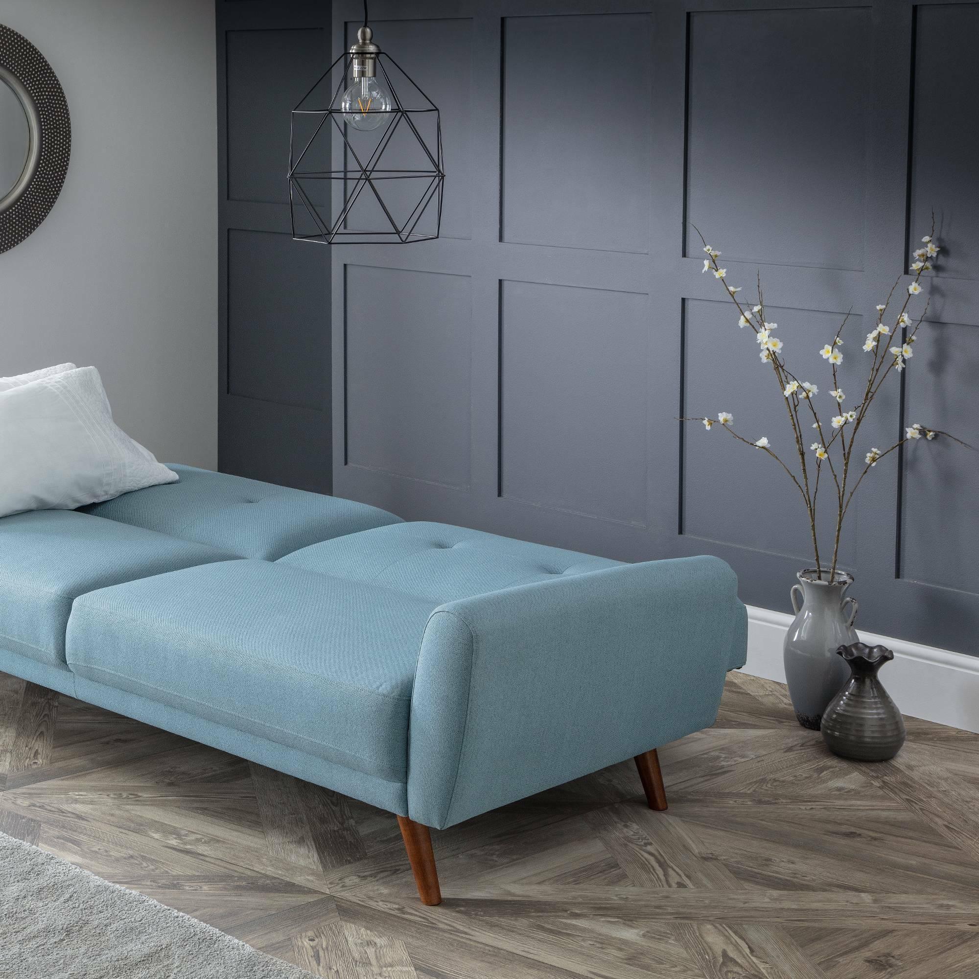 Monza blue sofabed in modern living room with grey paneled wall and wooden flooring