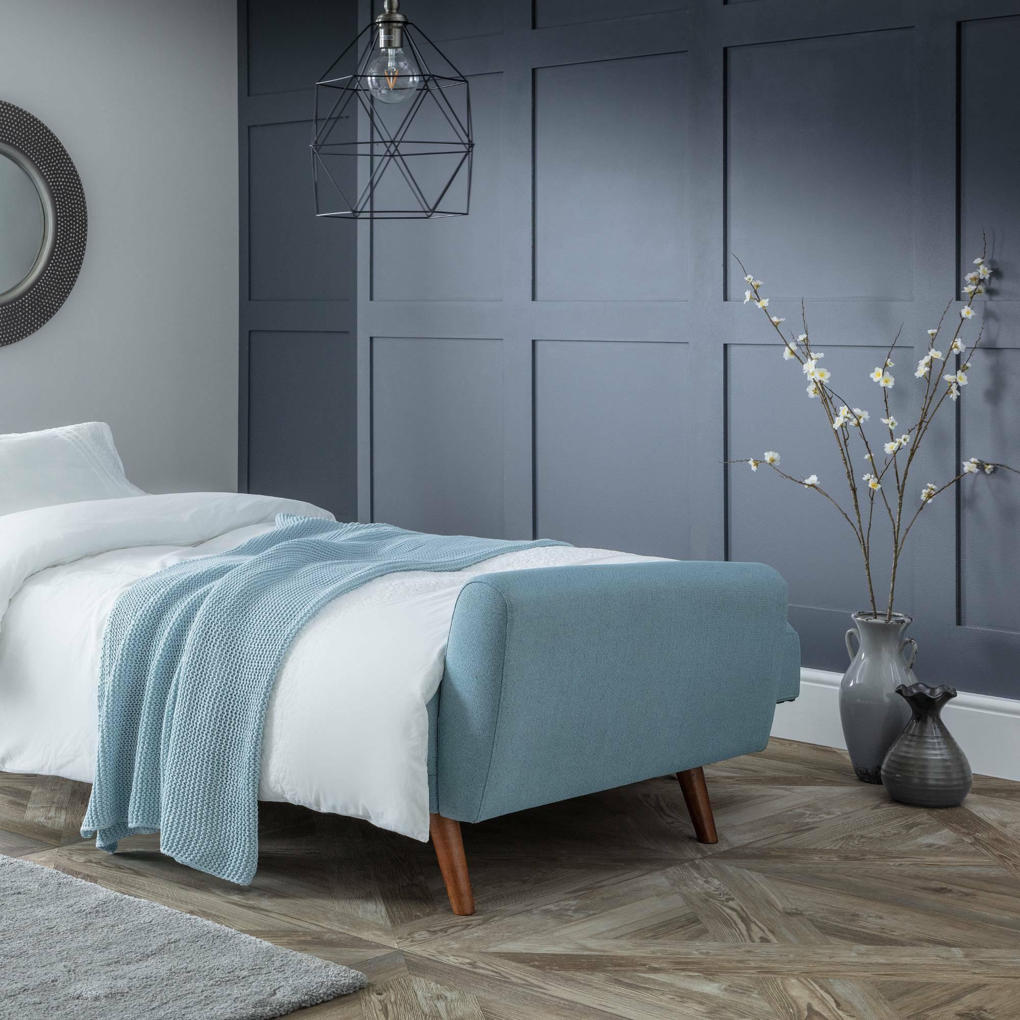 Monza blue sofabed extended with white bedding in modern room with wood flooring