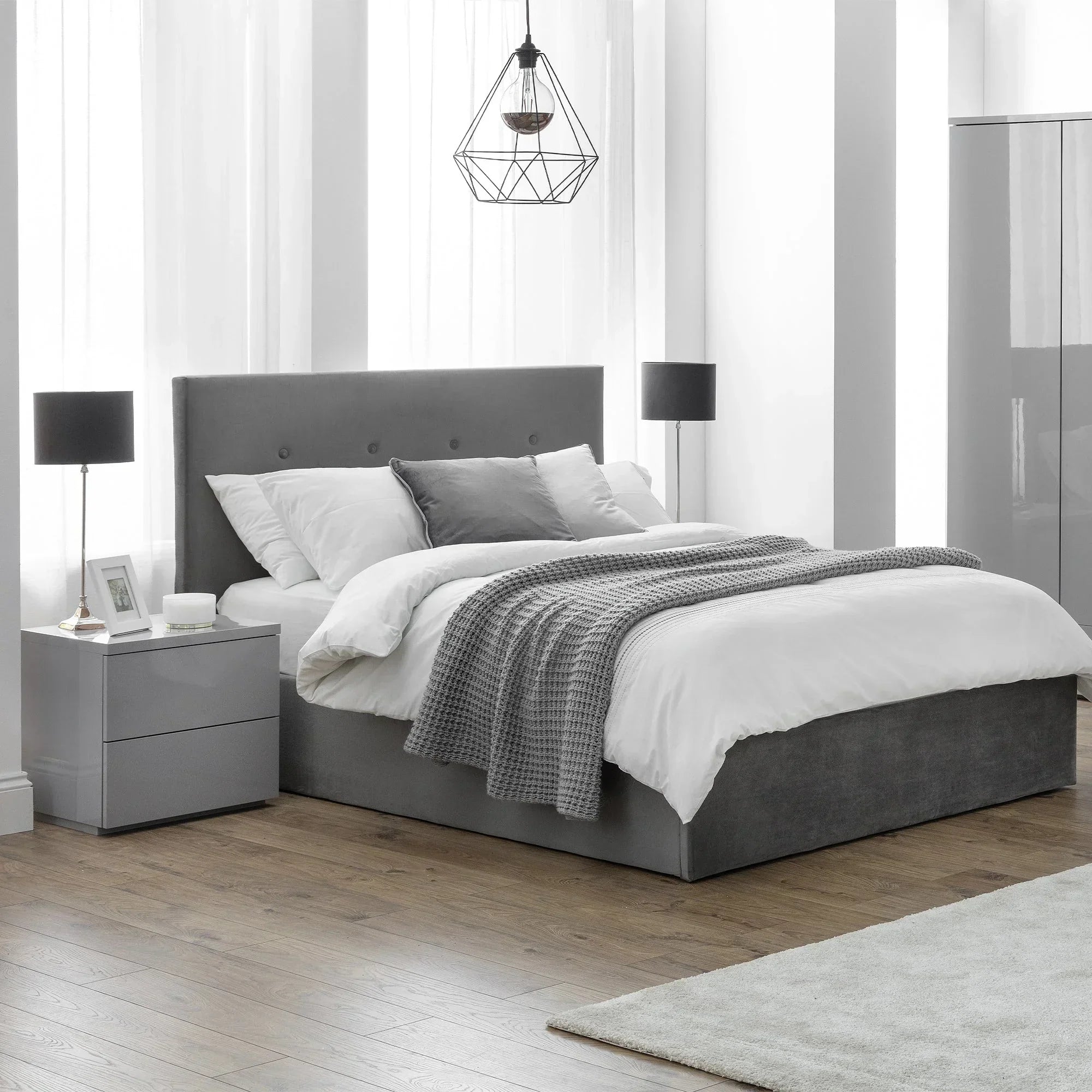Grey upholstered bed with buttoned headboard, white bedding and throw in minimalist bedroom
