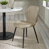 Beige upholstered dining chair with vertical stitching and black tapered metal legs beside round white table