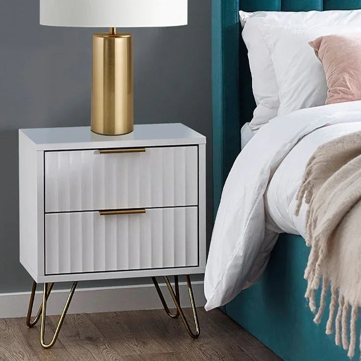 Matt white two drawer bedside table with gold handles and lamp beside bed