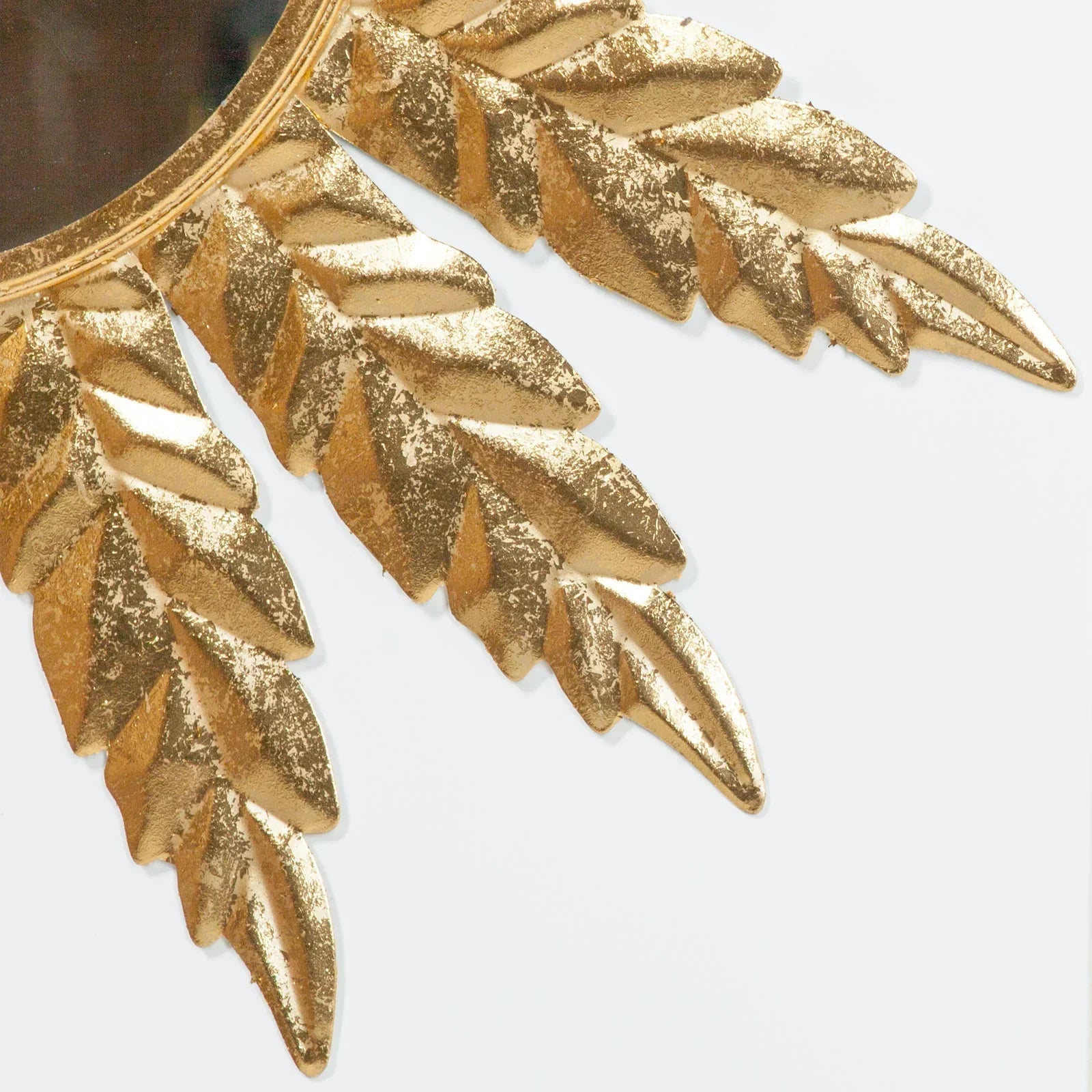 Gold leaf detail on decorative wall mirror with textured metallic finish