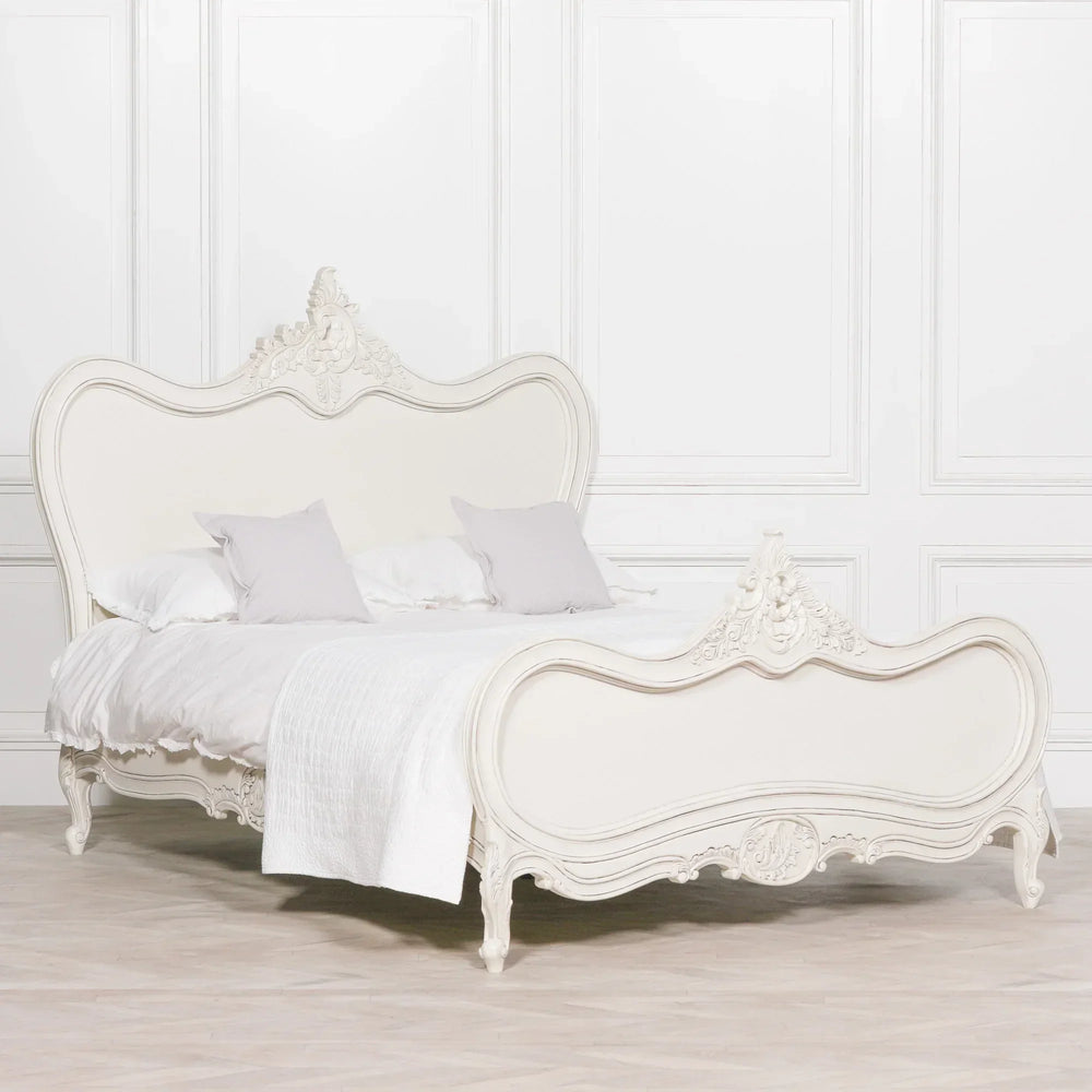 Ornate white wooden bed frame with carved detailing in classic style, white bedding and pillows