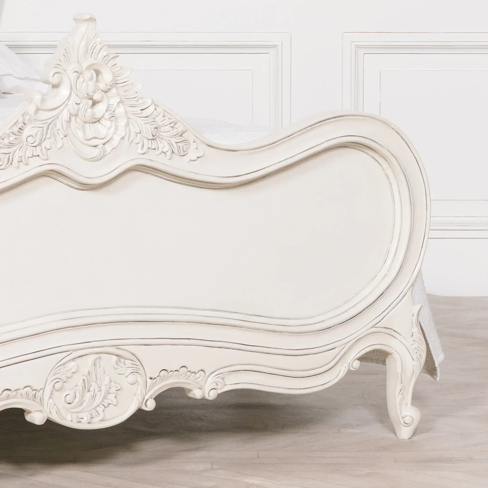 Cream French style bed frame with ornate carved detailing and curved footboard