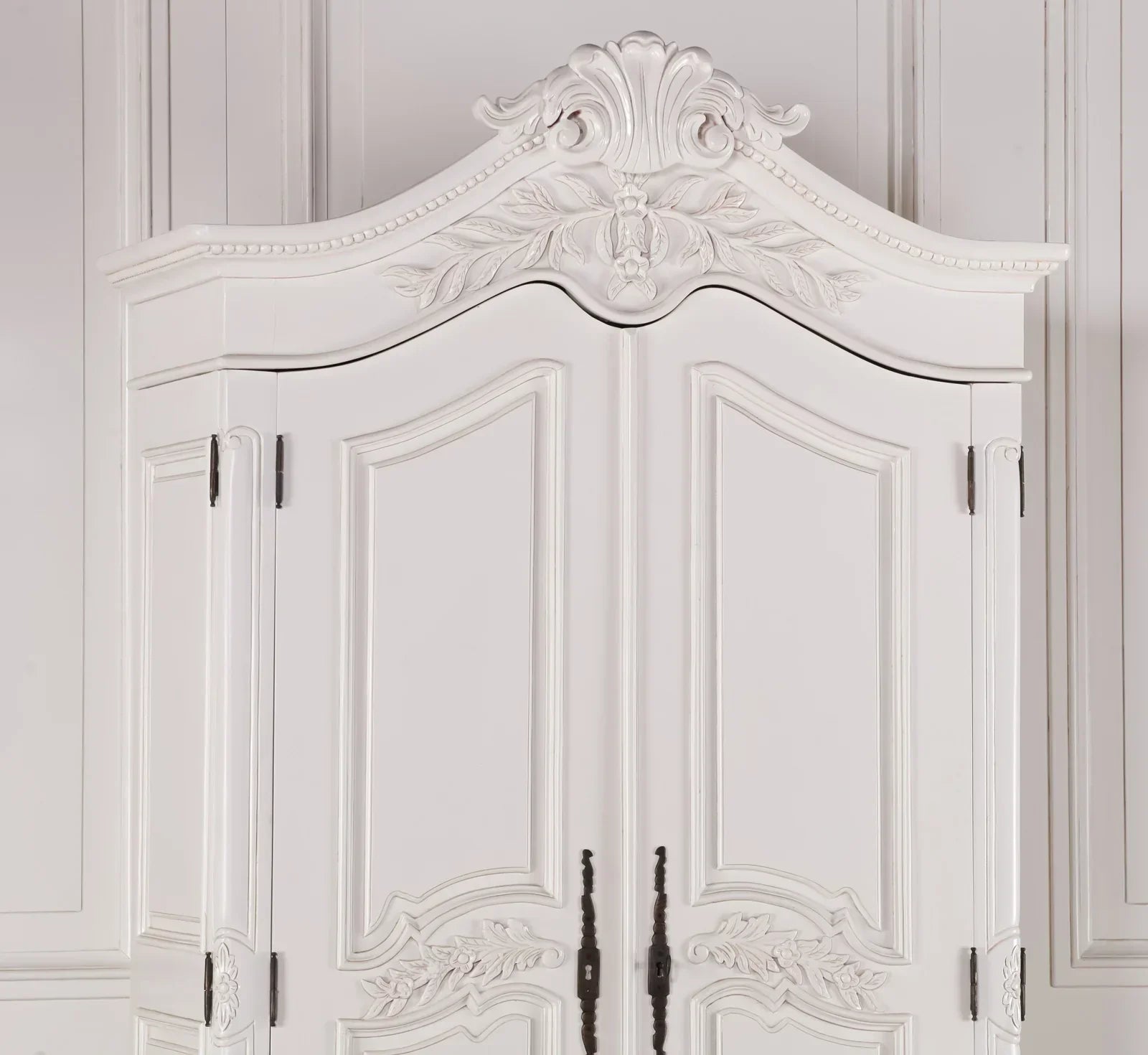 White ornate wardrobe with carved detailing and decorative top panel