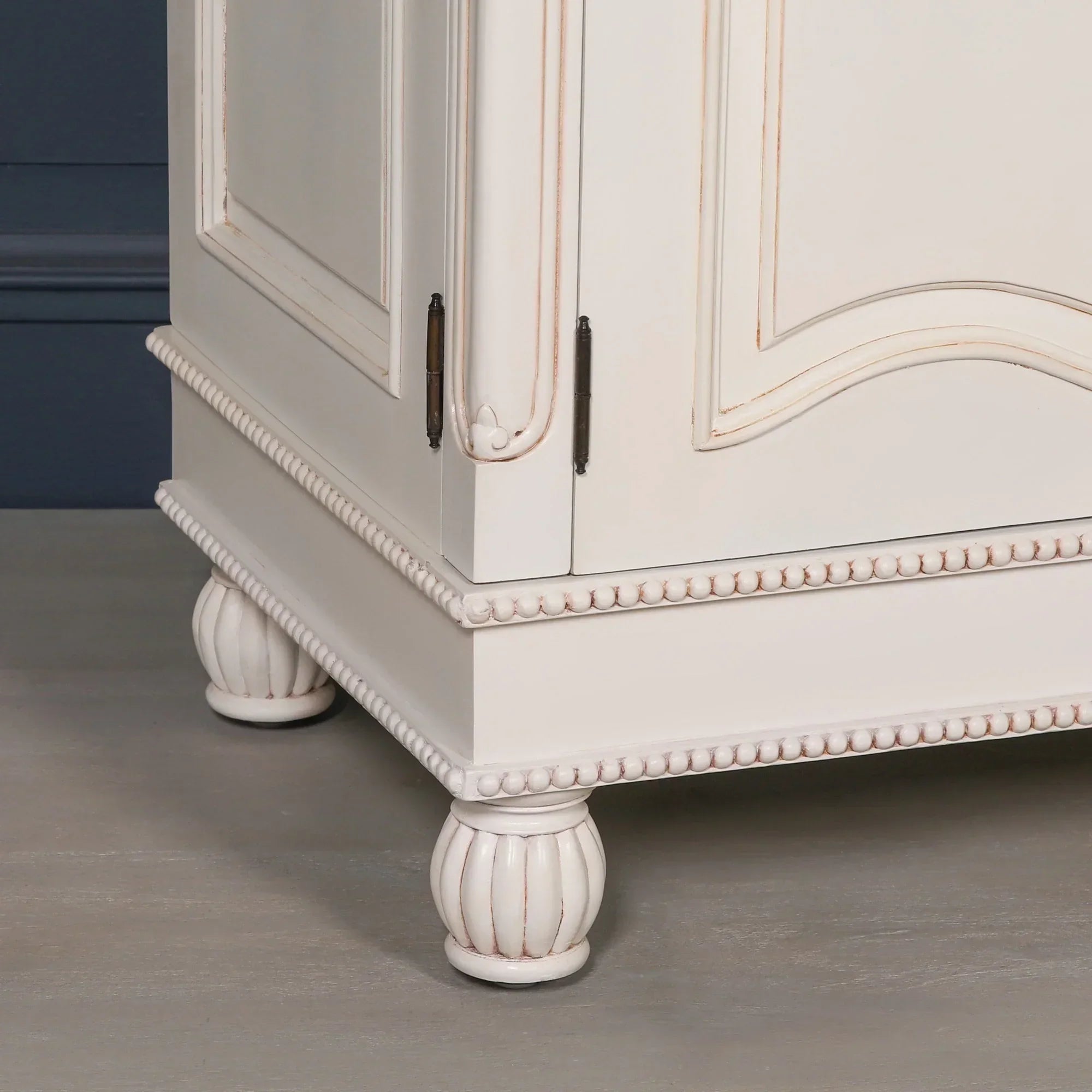 Cream painted furniture cabinet corner with carved wooden feet and decorative trim detail