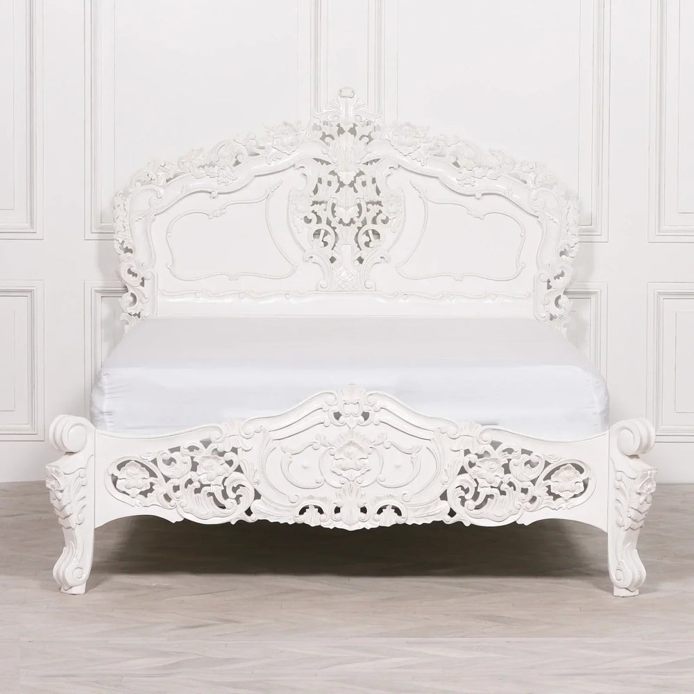 White ornate carved bed frame with intricate headboard and footboard, classic bedroom style